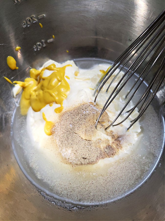 stainless mixing bowl with ingredients to make the creamy dressing for macaroni salad before whisking